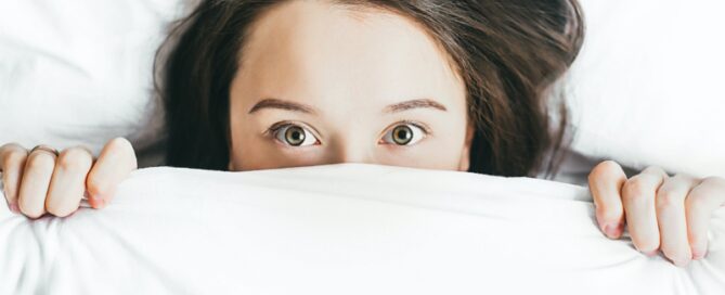 Woman looking out from under her duvet